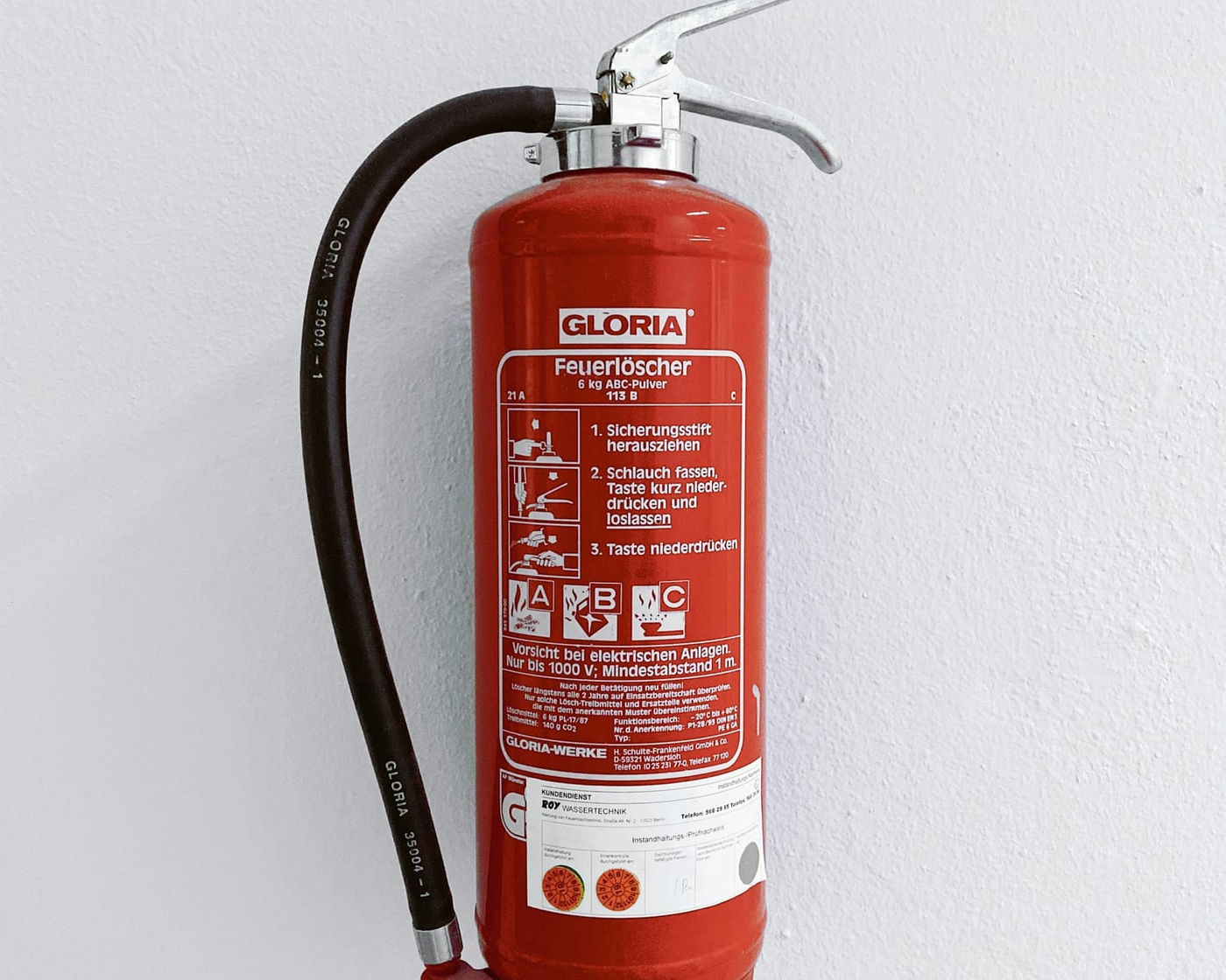 Roter Feuerlöscher an einer weißen Wand