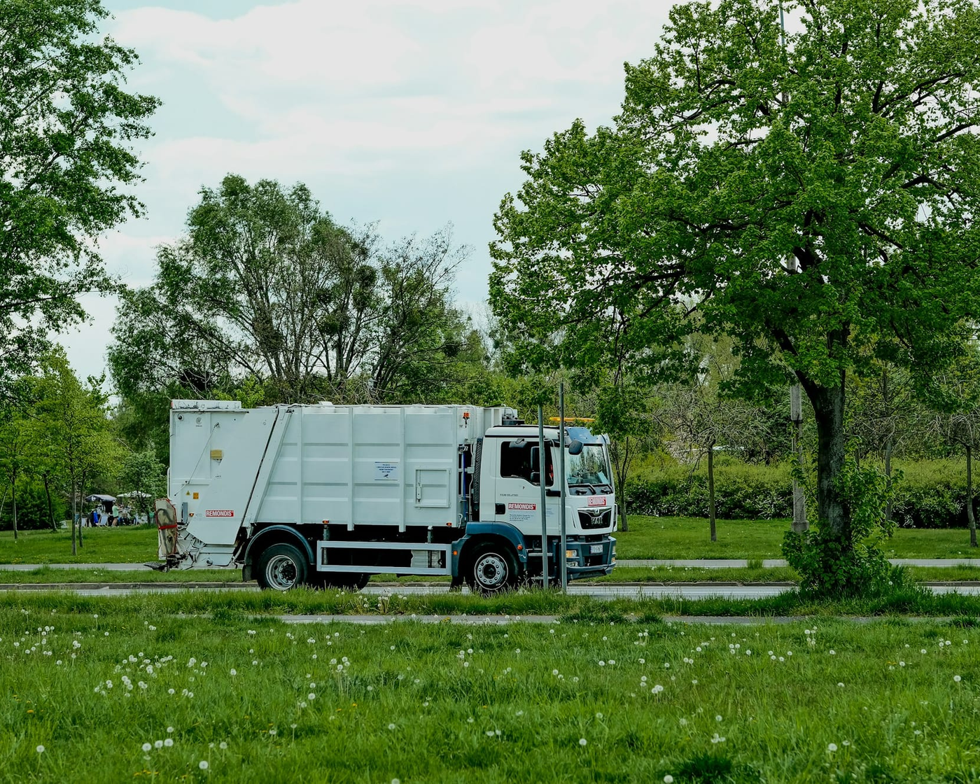 Entsorgungsfahrzeug auf einer Straße im Grünen