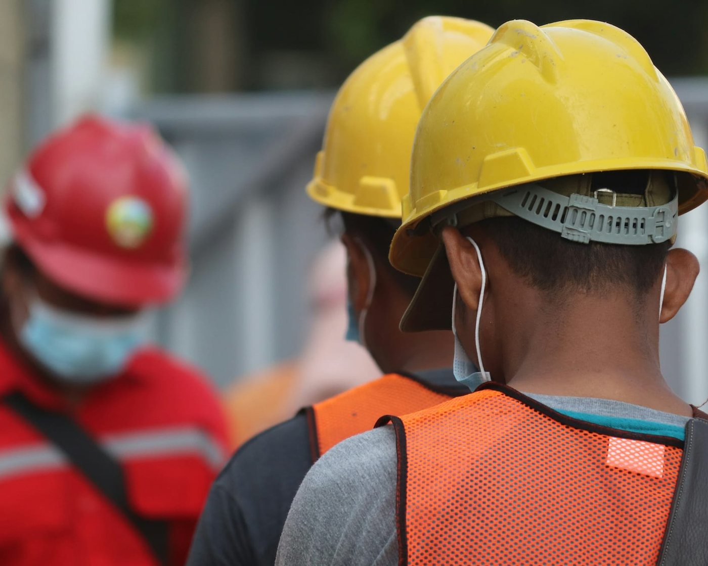 Externe Arbeitskräfte mit Schutzhelmen auf einem Firmengelände