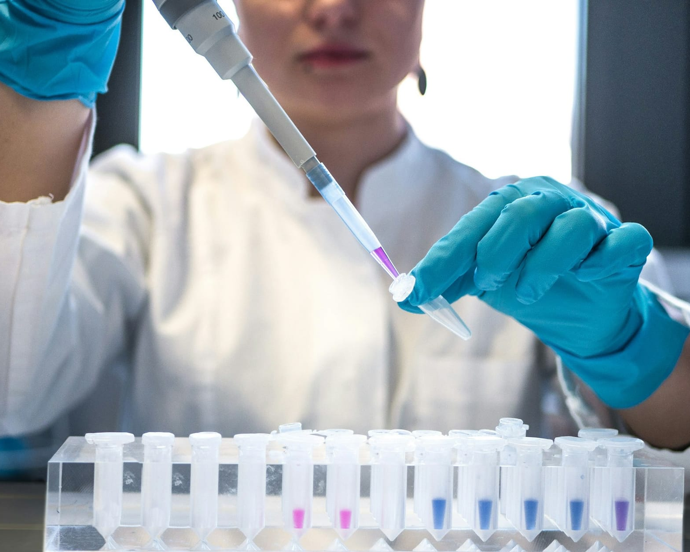 Laborantin füllt mit einer Pipette Proben in Röhrchen